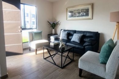 Interior casa grande sillones oscuros mesa decoración 