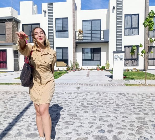 Persona asesor mostrando llaves de casa nueva en residencia privada con casas de fondo